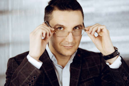 Friendly adult businessman in grey jacket. Business headshot or portrait in sunny officeの写真素材