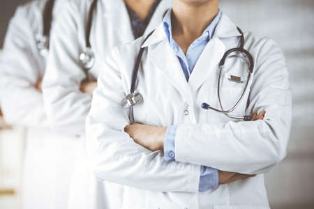 Group of modern doctors standing as a team with arms crossed in sunny hospital and ready to help patients. Medical help, insurance in health careの写真素材