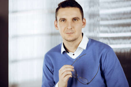 Friendly adult businessman in blue sweater. Business headshot or portrait in sunny officeの写真素材