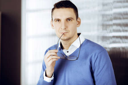 Friendly adult businessman in blue sweater. Business headshot or portrait in sunny officeの写真素材