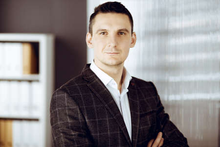 Friendly adult businessman in grey jacket. Business headshot or portrait in sunny officeの写真素材