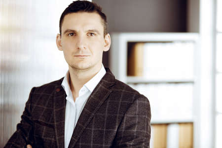Friendly adult businessman in grey jacket. Business headshot or portrait in sunny officeの写真素材