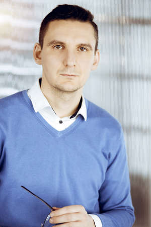 Friendly adult businessman in blue sweater. Business headshot or portrait in sunny officeの写真素材