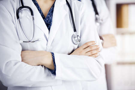 Group of modern doctors standing as a team with arms crossed in sunny hospital and ready to help patients. Medical help, insurance in health careの写真素材