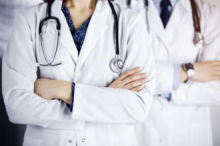Group of modern doctors standing as a team with arms crossed in sunny hospital and ready to help patients. Medical help, insurance in health careの写真素材