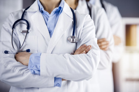Group of modern doctors standing as a team with arms crossed in sunny hospital and ready to help patients. Medical help, insurance in health careの写真素材