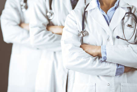 Group of modern doctors standing as a team with arms crossed in hospital office and ready to help patients. Medical help, insurance in health care, best disease treatment and medicine conceptの写真素材