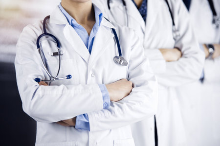 Group of modern doctors standing as a team with arms crossed in sunny hospital and ready to help patients. Medical help, insurance in health careの写真素材
