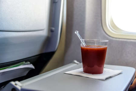 glas of tomato juice on a table in an airplane close to the airplane windowの写真素材
