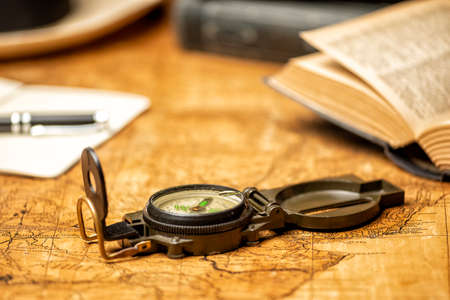 old expedition map with compass notebook, books and panama hat