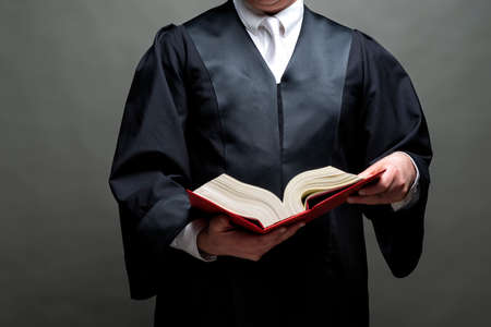 german lawyer with a classical black robe, white tie and bookの写真素材