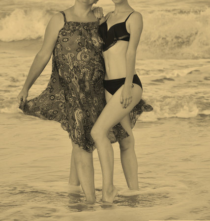 Two women mothers and daughter sitting on the steps near the sea near the beach summer people one in red dress second in blue with polka dot spotsの写真素材