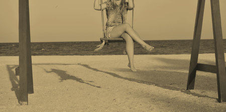 Middle Aged Woman Riding Swing On Sea And Beach Visible Man Legs Imagine Water Sky Beautiful 1の写真素材