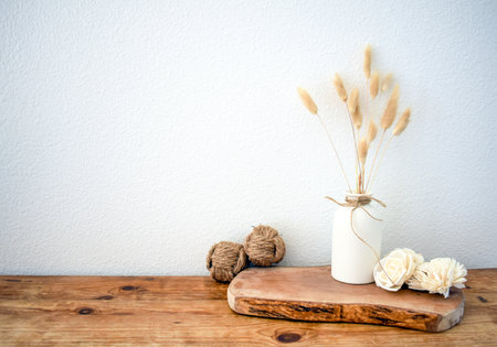 Stylish composition of table with beads and flowers and crown, bench in retro style, clay vases and crockery. Rustic inspiration. Summer vibes. Beige wood table.の写真素材