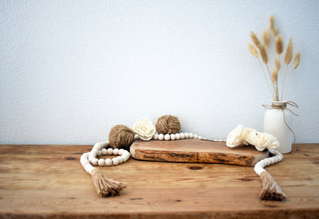 Stylish composition of table with beads and flowers and crown, bench in retro style, clay vases and crockery. Rustic inspiration. Summer vibes. Beige wood table.の写真素材