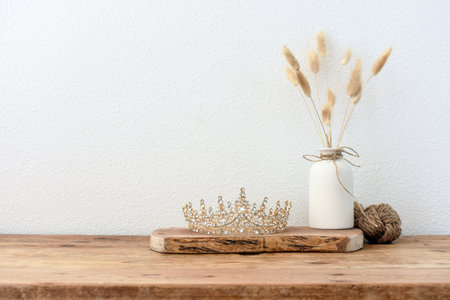 Stylish composition of table with beads and flowers and crown, bench in retro style, clay vases and crockery. Rustic inspiration. Summer vibes. Beige wood table.の写真素材
