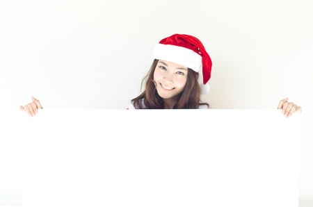 Asian Christmas woman wearing Santa hat over billboard sign, isolated on white background  の写真素材