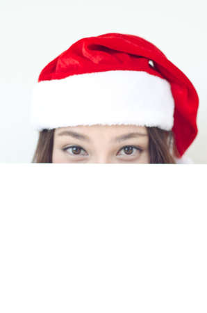Asian Christmas woman wearing Santa hat over billboard sign, isolated on white background  の写真素材