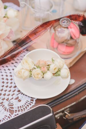 Delicate roses in a white porcelain Cup on a saucer in the decor of a wedding or birthdayの写真素材
