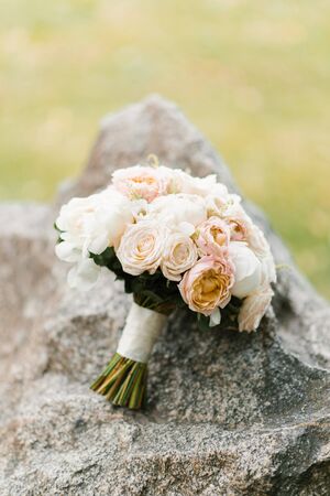 A delicate wedding bouquet lies on a stoneの写真素材