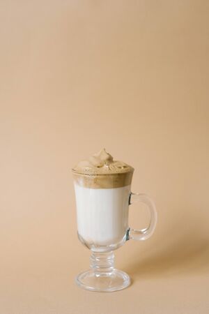 Beautiful dalgon drink coffee with foam in a transparent mug on a beige backgroundの写真素材