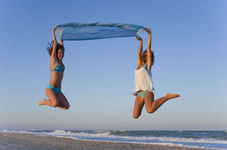 Two girls soaring in the sky on the blue scarfの写真素材