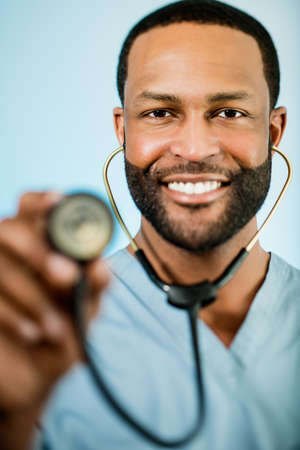Studio shot of a young African American doctor holding up a stethoscope.の写真素材