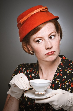 A woman in retro garb drinking a cup of tea.の写真素材