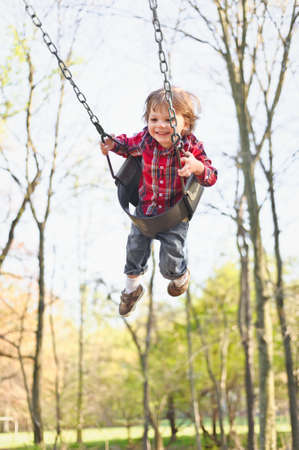 A young toddler boy swinging in the fall.の写真素材