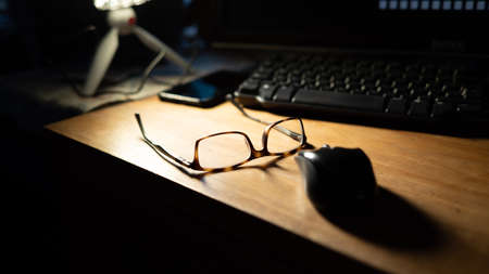 Glasses on a desk with a mouse, keyboard, Phone and Manfrotto Pixi tripod. The glasses are...
