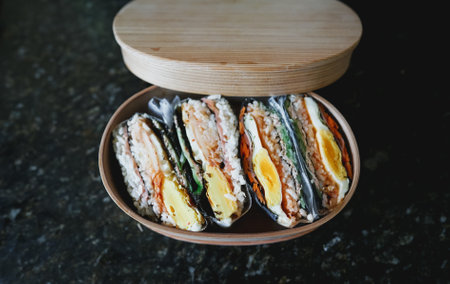 Sushi roll with salmon and egg in wooden box on black backgroundの写真素材