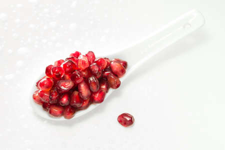 Pomegranate seeds in a spoon on the whiteの写真素材