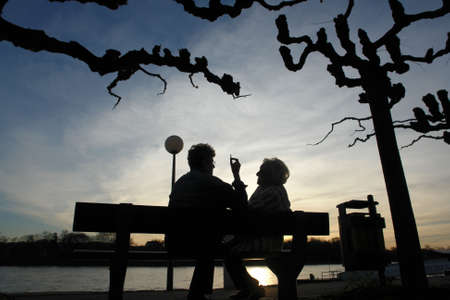 Senior women at a bench during sunset chattingの写真素材