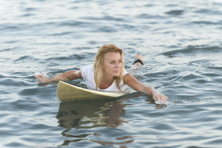 Beautiful woman with the surf board when the sun falls in the beach