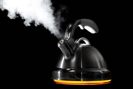 Tea kettle with boiling water on black background. Heater glow under the tea kettle. の写真素材