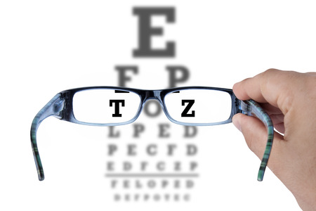 Hand holding glasses and reading eye chart test vision on whiteの写真素材