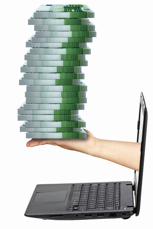 Hand holding pile of packs of 100 euro banknotes coming out from laptop isolatedの写真素材
