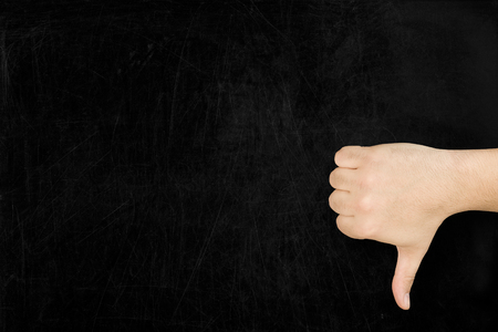 Male hand thumb down on used blank blackboard