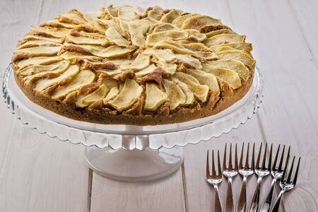Apple pie cake on glass cake stand on white wooden tableの写真素材