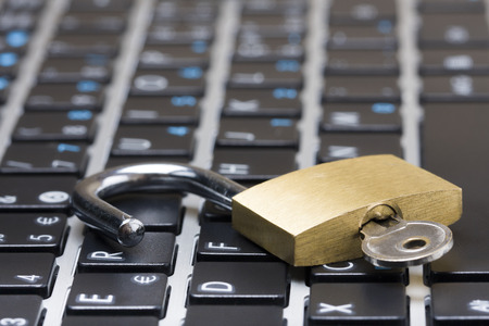 Computer security concept with an open padlock with key on the keyboardの写真素材