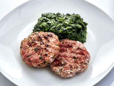 Hamburgers with spinach on plateの写真素材