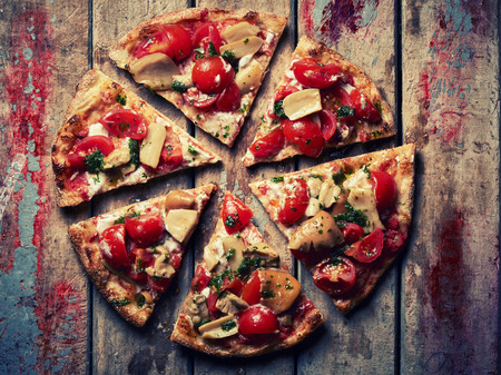 Slices of Pizza with mushrooms tomatoes on grunge wooden tableの写真素材