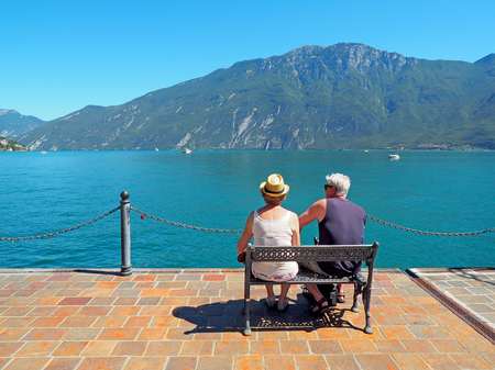 Limone sul Garda, Italy - August 2016: senior couple sitting on a bench admiring Garda Lakeのeditorial素材