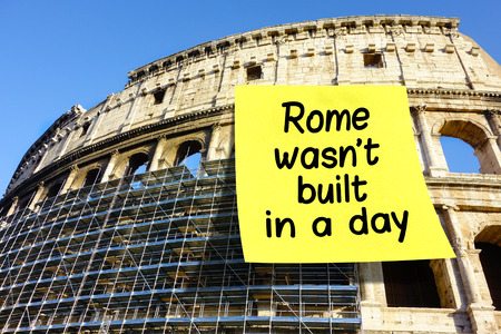 Idiom Rome wasn't built in a day on large postit affixed on Colosseum in Romeの写真素材