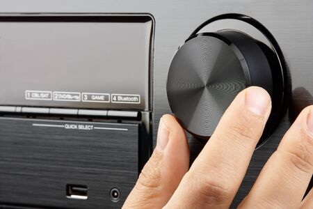 Closeup male hand turning blank knob of amplifier