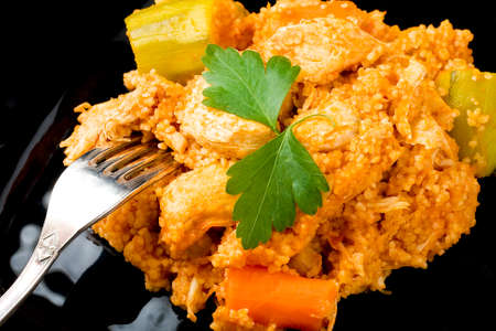 Couscous presented on black plate and silver fork on white wooden tableの写真素材