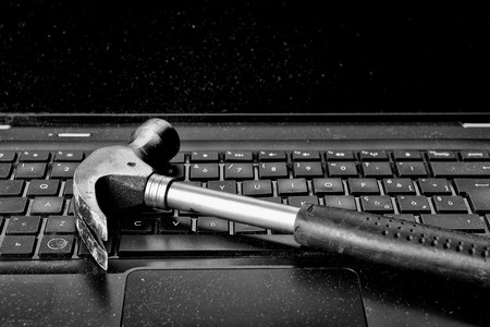 Hammer laying on keyboard of broken laptopの写真素材