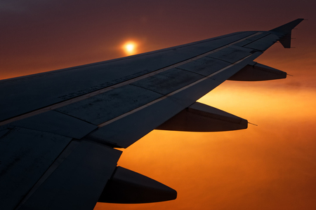 Plane flying silhouette wing at sunset or sunriseの写真素材
