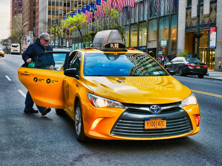 New York City, USA - April 2018: Man getting on yellow taxi in Manhattanのeditorial素材