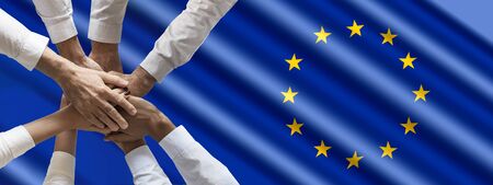 Close up top view of business people putting their hands together on European Union flag. Stack of hands. Unity and teamwork concept.の写真素材